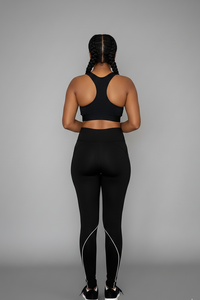 Person wearing a black sports bra and leggings set on a gray background