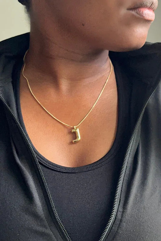Person wearing a gold necklace with a pendant